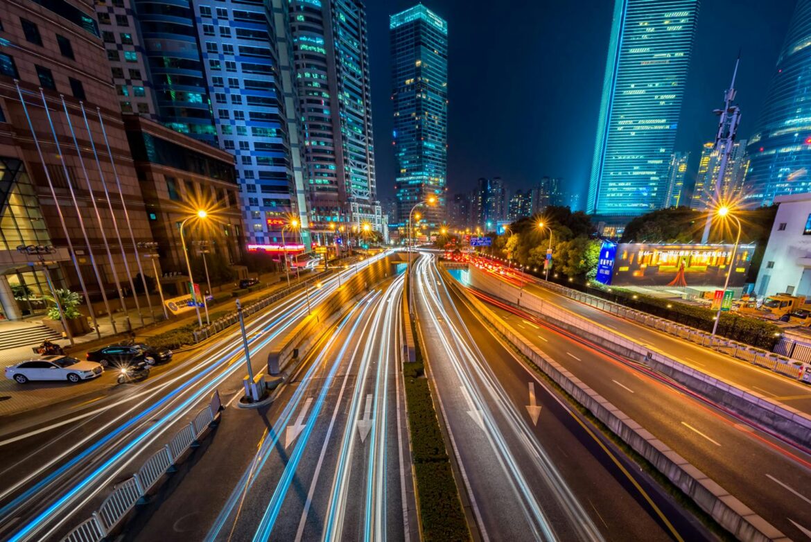 Dynamic long exposure night shot of urban cityscape with vibrant light trails and towering skyscrapers.